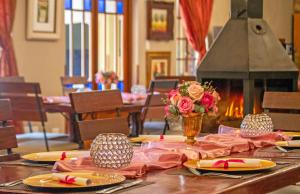 a table with plates and a vase of flowers and a fireplace at Afrique Boutique Hotel O.R. Tambo in Boksburg