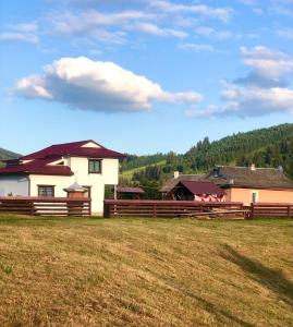 a white house with a fence in a field at ЮрДар in Iltsi