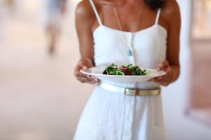 Una donna con un vestito bianco che tiene un piatto di cibo di Iberostar Selection Playa de Palma a Playa de Palma