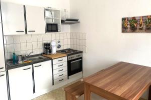 uma pequena cozinha com armários brancos e uma mesa de madeira em Cozy Apartments in Zwickau em Zwickau