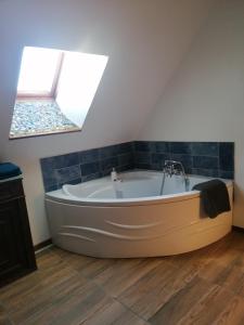 una gran bañera blanca en una habitación con 2 tragaluces. en Chambre Cosy, Nature, wifi et salle de bain en La Roche-Posay