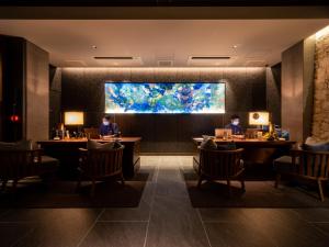 two people sitting at tables in a restaurant with a large aquarium at One Suite THE GRAND in Nakijin