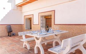 uma mesa de madeira com copos de vinho e dois bancos em Nice Home In Casarabonela With Kitchen em Casarabonela