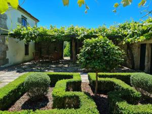 a garden with trimmed hedges in front of a house at Pazo de Eidian in Eidián