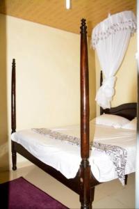 a bedroom with a four post bed with white sheets at Beautiful 1BR with Wi-Fi & secure parking in Kakamega