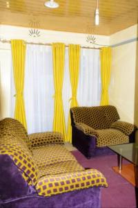 a living room with yellow curtains and a couch and a table at Beautiful 1BR with Wi-Fi & secure parking in Kakamega