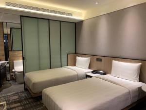台北市にあるホテル ミッドタウン リチャードソンのベッド2台とバスルームが備わるホテルルームです。
