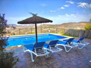 a group of chairs and an umbrella next to a pool at Balcón al Valle in El Gastor