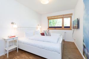 een slaapkamer met een wit bed en een raam bij Nienhagen in Nienhagen