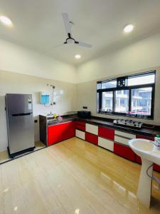 een keuken met rode en witte kasten en een koelkast bij White Tulip in Lonavala