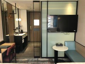 a bathroom with a television and a table and a sink at Hotel Midtown Richardson in Taipei
