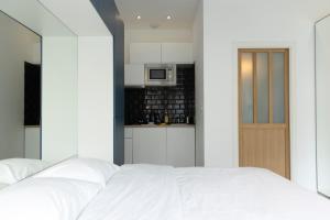a bedroom with a white bed and a kitchen at Studio moderne et confort au centre ville in Metz