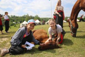 two girls are petting a cow in a field at Козацька Фортеця in Pliskachevka