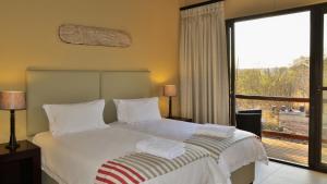 ein Schlafzimmer mit einem Bett und einem großen Fenster in der Unterkunft Mjejane Luxury Self-Catering Villa in Hectorspruit
