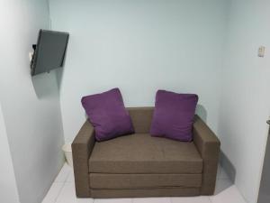 een bank met 2 paarse kussens in een kamer bij Susilo Residence 10 in Jakarta