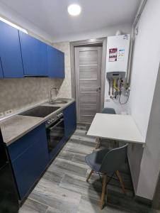 a kitchen with blue cabinets and a sink and a table at Studio Ali with parking in Zărneşti