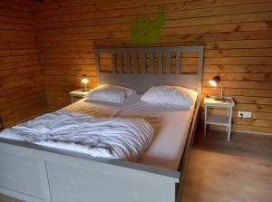 a large bed in a wooden room with two lamps at le sanglier in Bertogne