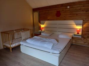 een slaapkamer met een bed met 2 lampen en een wieg bij le sanglier in Bertogne