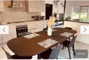 a dining room table with chairs and a vase of flowers at La Villa Bastogne Gîte 4 personnes in Bastogne