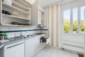 Spacious Central Apartments HOTING في زيورخ: مطبخ أبيض مع حوض ونافذة