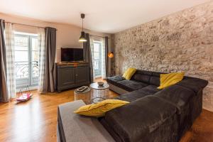sala de estar con sofá negro y pared de piedra en Les Gîtes du château - L Appartement du Roi - Magnifique Appartement face au château en Nérac