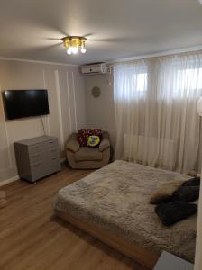 a bedroom with a bed and a chair and a television at Scandinavian Home in Bucharest City Center in Bucharest