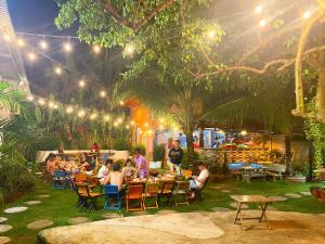 a group of people sitting at tables in a garden at night at Hồ Cốc Homestay in Ho Coc