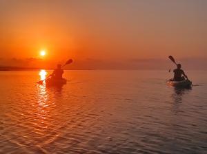 two people in kayaks on the water at sunset at Pensiunea Cuplu Călător in Jurilovca