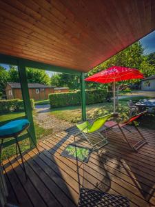 two chairs and a red umbrella on a deck at hôtel gites le clos du moulin in Terrasson-Lavilledieu