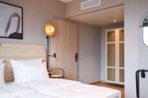 a bedroom with a white bed and a window at Scandic München Macherei in Munich