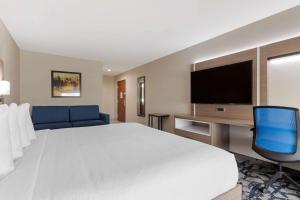 a hotel room with a bed and a flat screen tv at Comfort Inn & Suites Muskogee in Muskogee