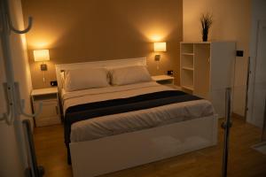 een slaapkamer met een wit bed met 2 tafels en 2 lampen bij Living Room Schiavonea in Marina di Schiavonea