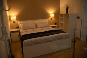 a bedroom with a white bed with two tables and two lamps at Living Room Schiavonea in Marina di Schiavonea