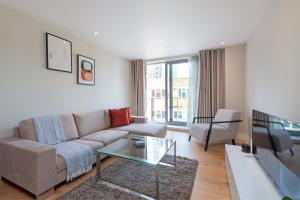 uma sala de estar com um sofá e uma mesa de vidro em Stayo Apartments Southbank em Londres