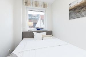 una camera con un letto bianco e una barca a vela alla finestra di Blankwasserweg 57 Wohnung 5 a Grömitz