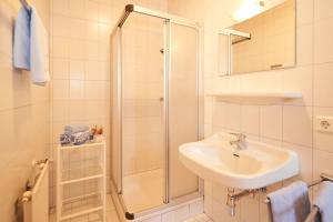 a white bathroom with a sink and a shower at Mittersteghof, in Filzmoos