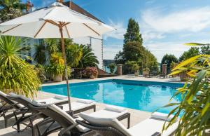 a swimming pool with lounge chairs and an umbrella at St Brelade's Bay Hotel in St Brelade