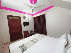 a bedroom with a white bed and a ceiling fan at Gulshan Family Guest House Near Millennium Mall in Karachi