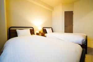 two beds in a small room with white sheets at Branchera Naha 1107 in Naha +51 photos