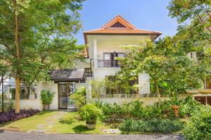 una imagen de una casa con árboles delante de ella en Da Nang Paradise Center My Khe Beach Resort & Spa en Da Nang