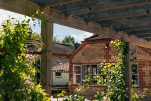 ein Backsteinhaus mit einer hölzernen Pergola in der Unterkunft The Sparsholt Barn in Wantage