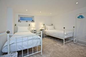 2 camas en una habitación con paredes blancas en The Mews, Tresean, en Newquay