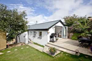 a white cottage with a garden and a patio at The Mews, Tresean in Newquay