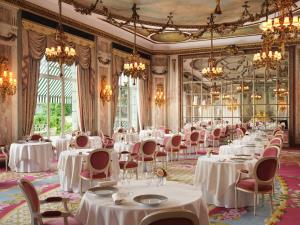 a dining room with white tables and chairs and chandeliers at The Ritz London in London