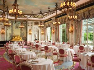 a dining room with white tables and chairs and chandeliers at The Ritz London in London