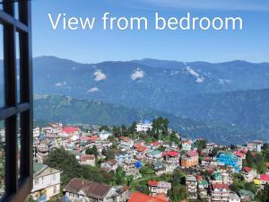una ventana con vistas a una ciudad con montañas en PRATIMA HOMESTAYS, en Darjeeling