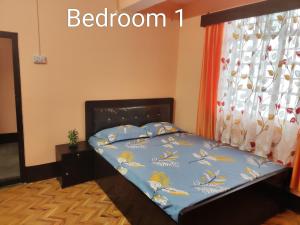 1 cama con edredón azul y ventana en PRATIMA HOMESTAYS, en Darjeeling