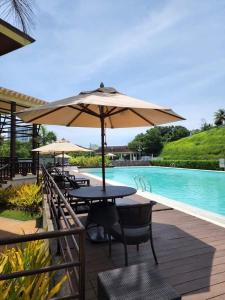 uma mesa com um guarda-sol ao lado de uma piscina em Aloha Hale One Oasis Cdo em Cagayan de Oro