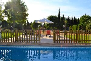 uma piscina com uma cerca e um guarda-sol em 5 bedrooms villa with private pool jacuzzi and enclosed garden at Fernan Caballero em Fernancaballero