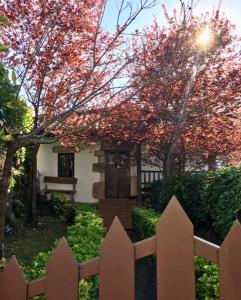 uma cerca branca em frente a uma casa com uma árvore em HdeC Hosteria de Castañeda Alojamiento Turistico em Puente Viesgo